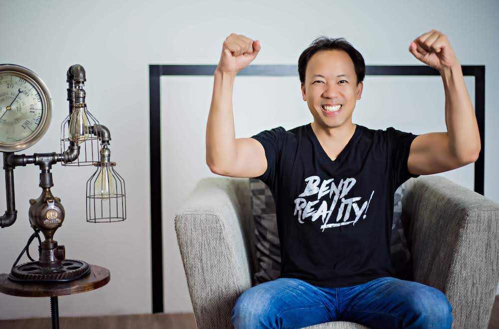 Jim Kwik, trainer of Mindvalley's Superbrain Quest, raising his arms in celebration