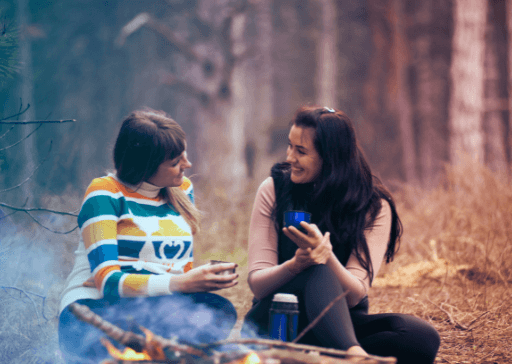 two women sitting by fire outdoors best hypothetical questions ever