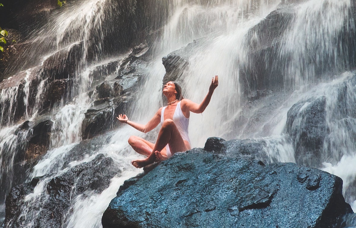 a woman sitting under the waterfall