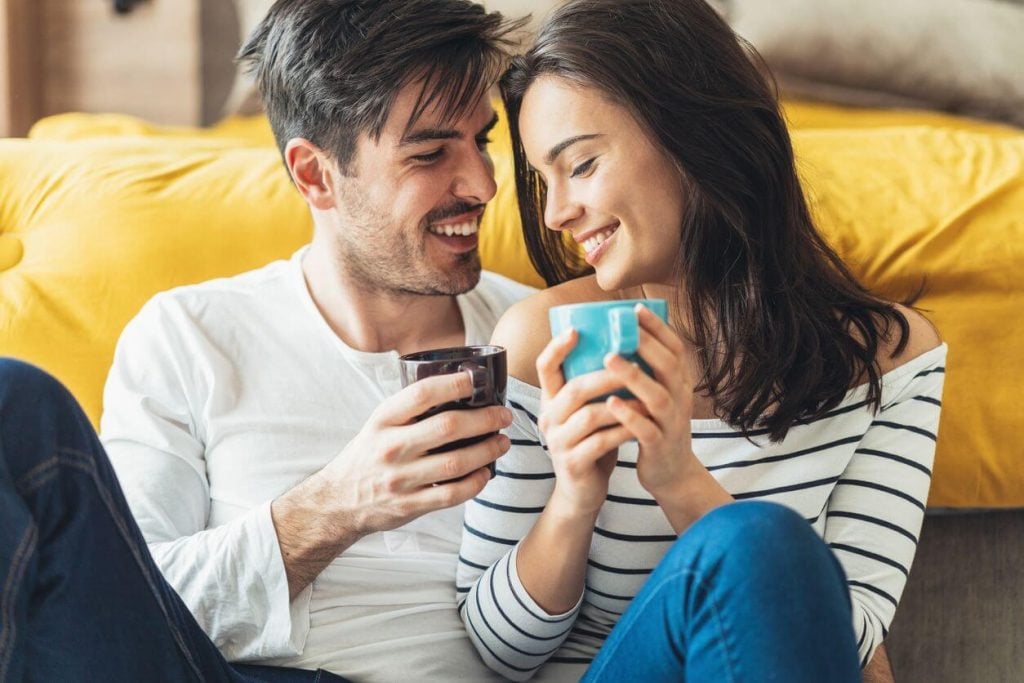 couple drinking coffee sitting close Signs of a Dominant Man 
