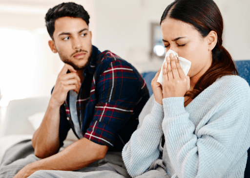 couple sitting on sofa woman blowing nose pet peeves
