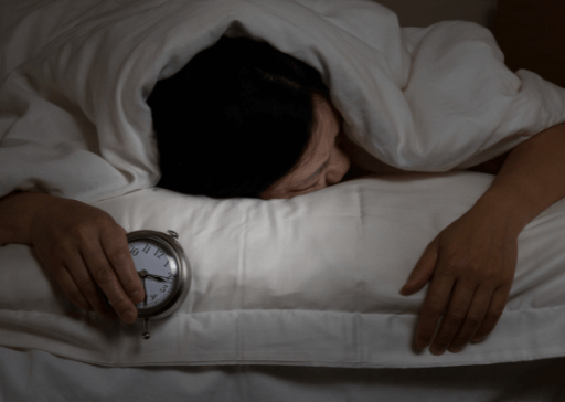 person in bed holding clock what to do when you can’t sleep and are bored